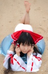 barefoot beach cosplay detached_sleeves hairbow hakurei_reimu lenfried miko one-piece_swimsuit swimsuit touhou rating:Safe score:1 user:nil!